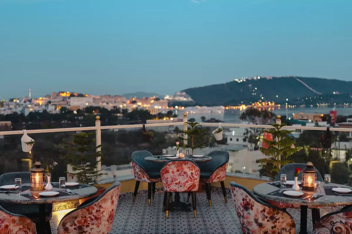 Candle-lit rooftop tables overlooking Udaipur at blue hour